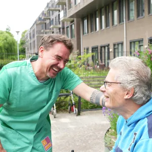 Zorgmedewerker en cliënt hebben plezier in de tuin