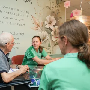 Client zit met medewerkers aan tafel in hospice van ViVa!