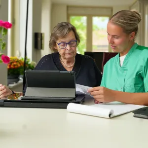 Zorgmedewerker van ViVa! zit samen met cliënt achter de computer en vraagt zorg aan