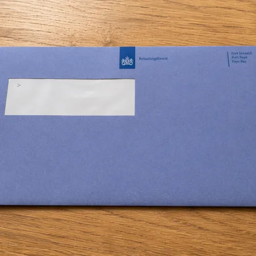 Blauwe envelop belastingdienst op houten tafel