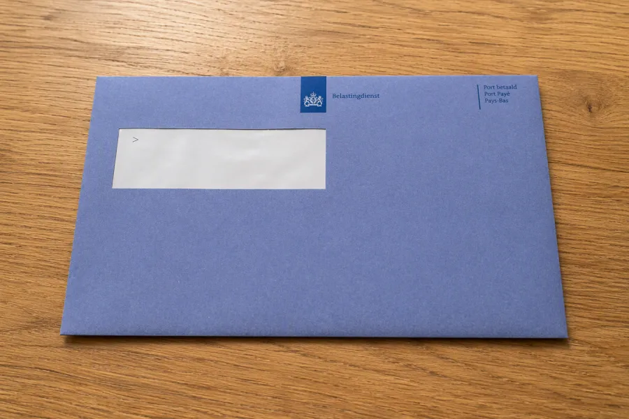 Blauwe envelop belastingdienst op houten tafel