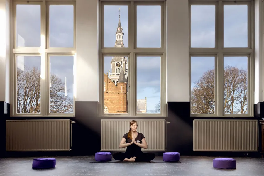 JaaaYoga eigenaresse Elles in de yogastudio met op de achtergrond de grote ramen met de kerk.jpeg